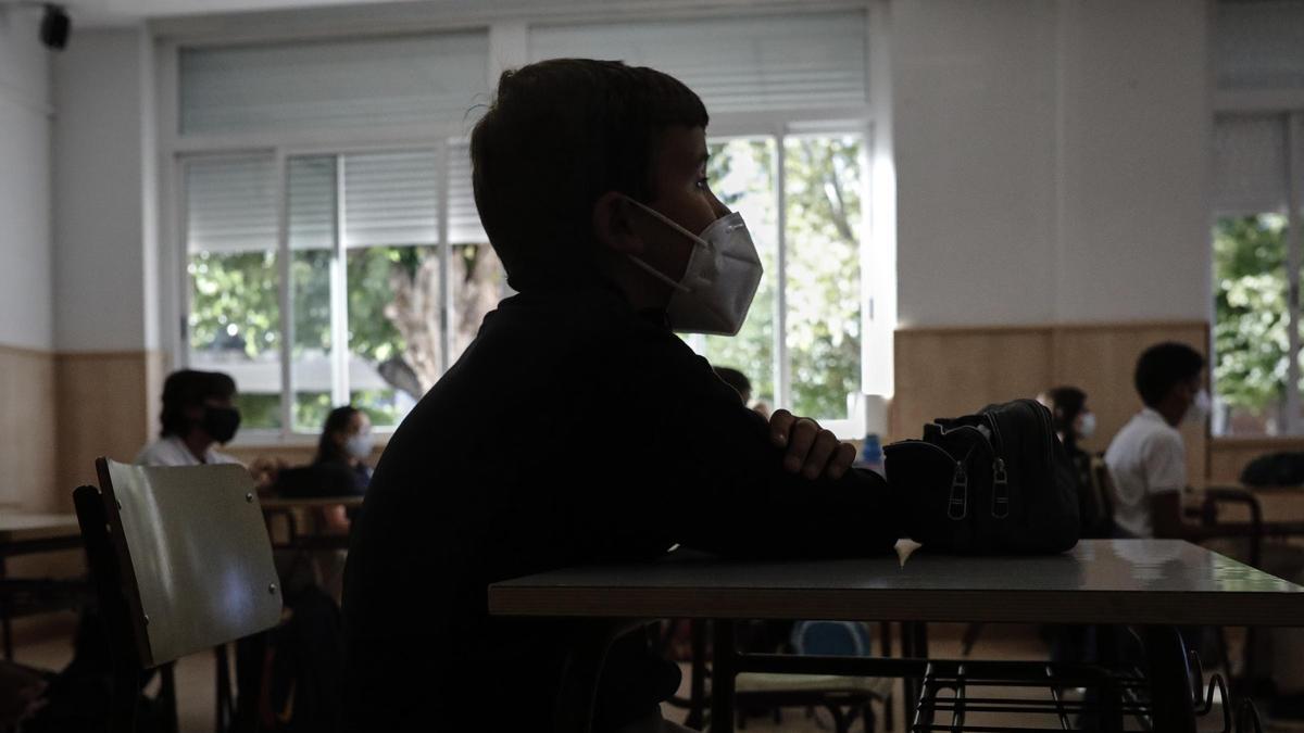 Un niño con mascarilla en un aula escolar.