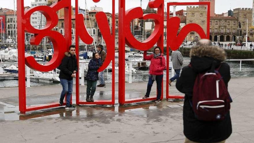 Unos turistas se fotografían en las populares &quot;letronas&quot; de Gijón.