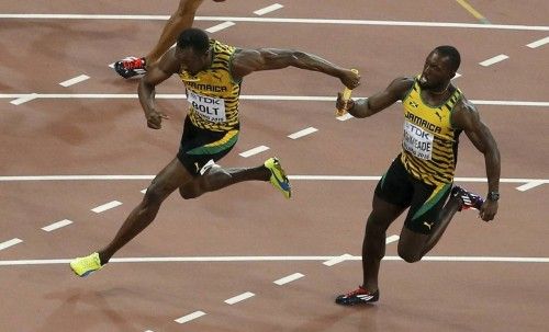 Bolt of Jamaica receives the baton from teammate Ashmeade as they compete in the men's 4 x 100 metres relay final during the 15th IAAF World Championships at the National Stadium in Beijing