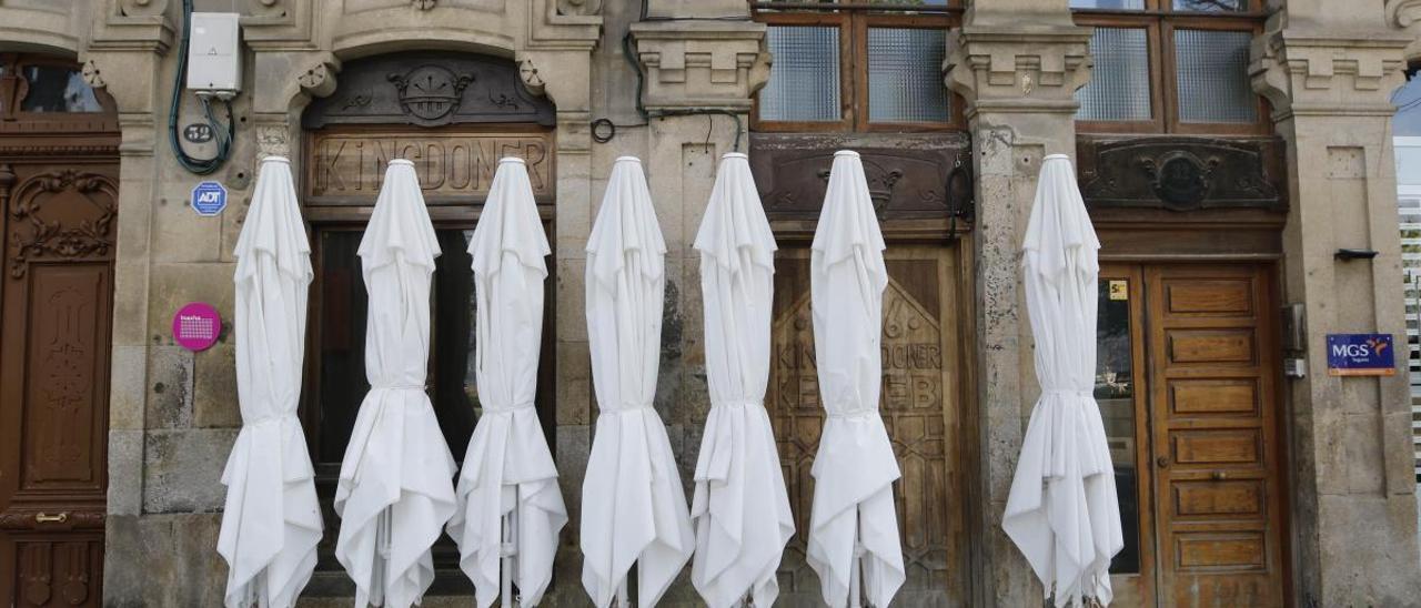 Sombrillas de terraza apiladas frente a una cafetería de Vigo. // Alba Villar