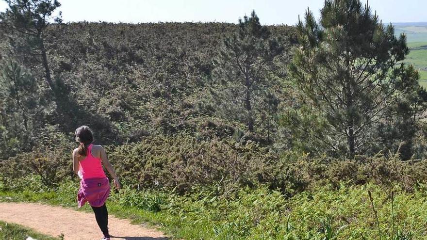 Una mujer camina por la senda de Luanco a Bañugues.