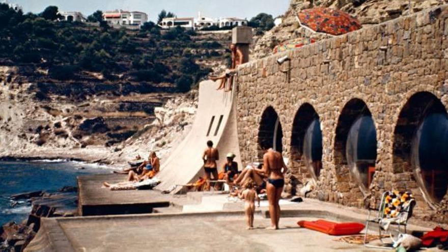 El Club Social funcionó durante los años 70 y 80 del pasado siglo, pero hoy es una ruina. En la imagen, se observa a los bañistas disfrutando de un edificio prácticamente metido en el mar y cuyos elementos más característicos son los grandes óculos.