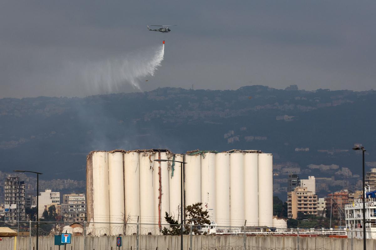 Un helicóptero del ejército libanés libera agua sobre los silos de grano gravemente dañados en el puerto de la capital, Beirut, el 31 de julio de 2022
