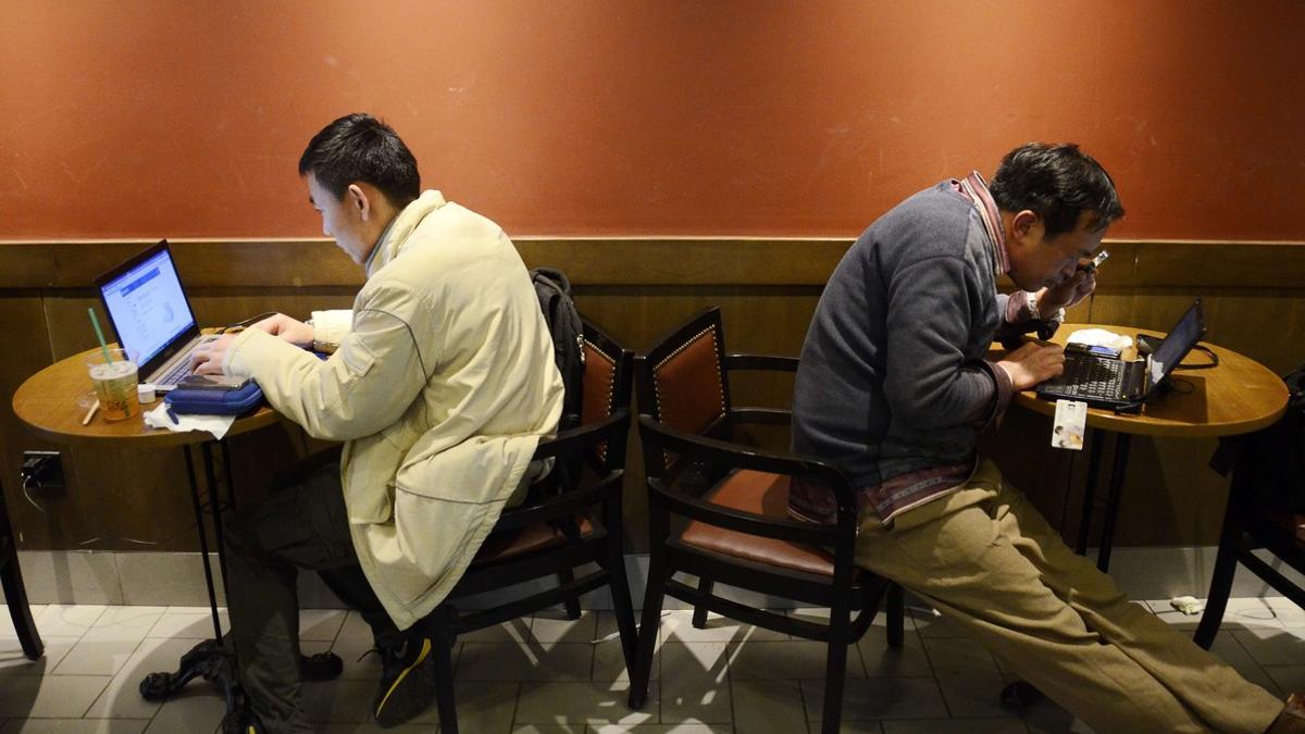 Dos hombres usan sus portátiles en un café de Shanghái.