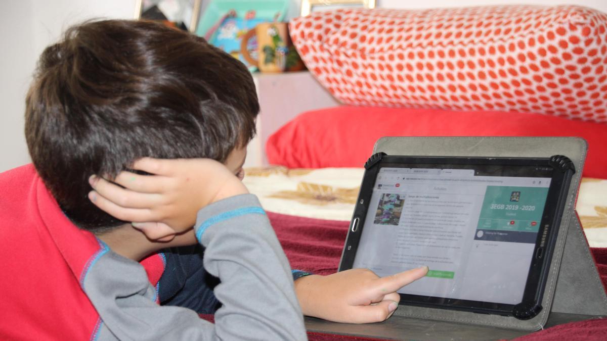 Un niño utiliza una tablet para hacer las actividades escolares.