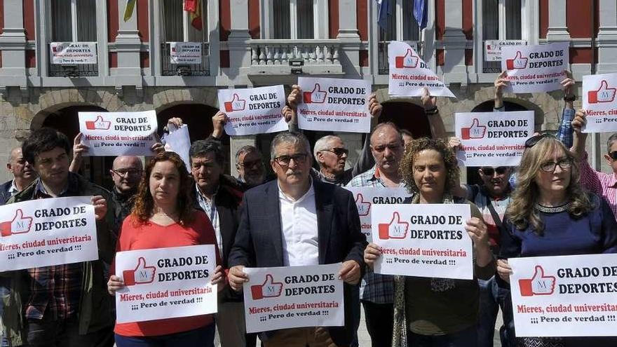 El alcalde de Mieres, en el centro, y representantes políticos, empresariales y vecinos muestran carteles de apoyo a la implantación del grado de Deporte en Barredo.