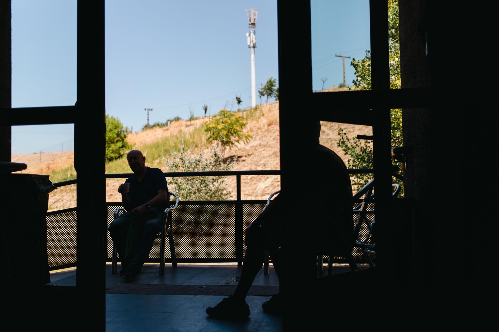 Residentes del Centro de acogida municipal para personas sin hogar Puerta Abierta buscan un respiro del calor a la entrada del edificio.