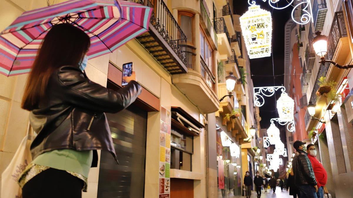 Una persona echa fotos a los adornos navideños de la calle en Murcia.