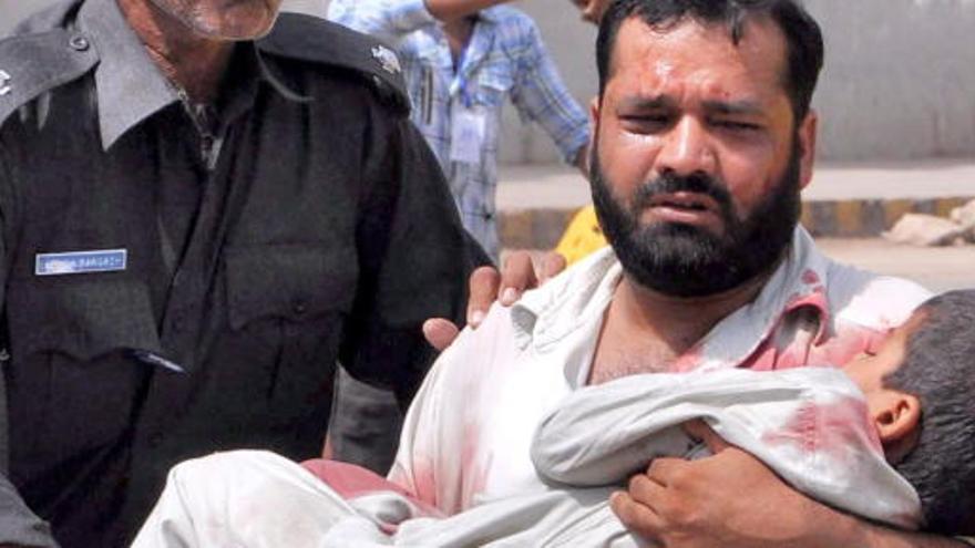 Un hombre sostiene a su hijo herido en Karachi.