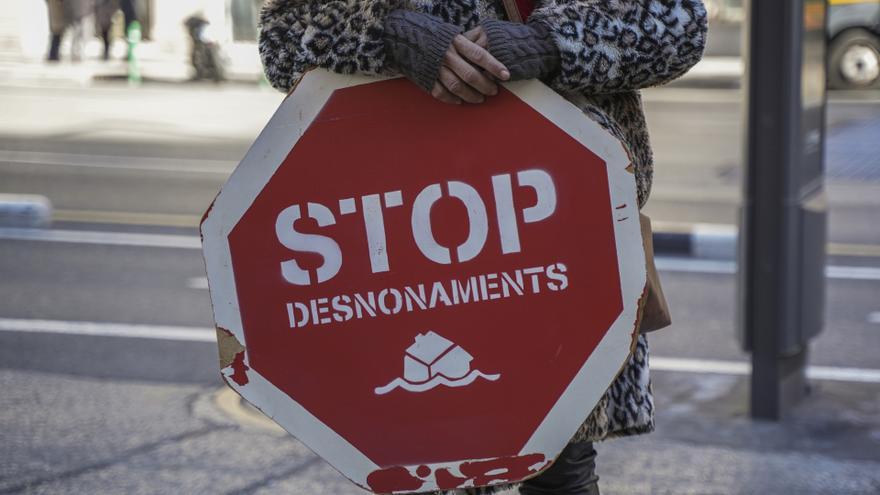 Una persona sujeta un cartel de 'Stop desnonamients' durante una concentración de la Plataforma de Afectados por la Hipoteca (PAH)