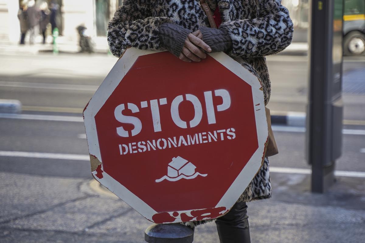 Archivo - Una persona sujeta un cartel de Stop desnonamients durante una concentración de la Plataforma de Afectados por la Hipoteca (PAH)