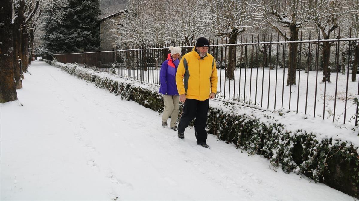 Dos vecinos de Camprodón paseando ante un paisaje nevado.