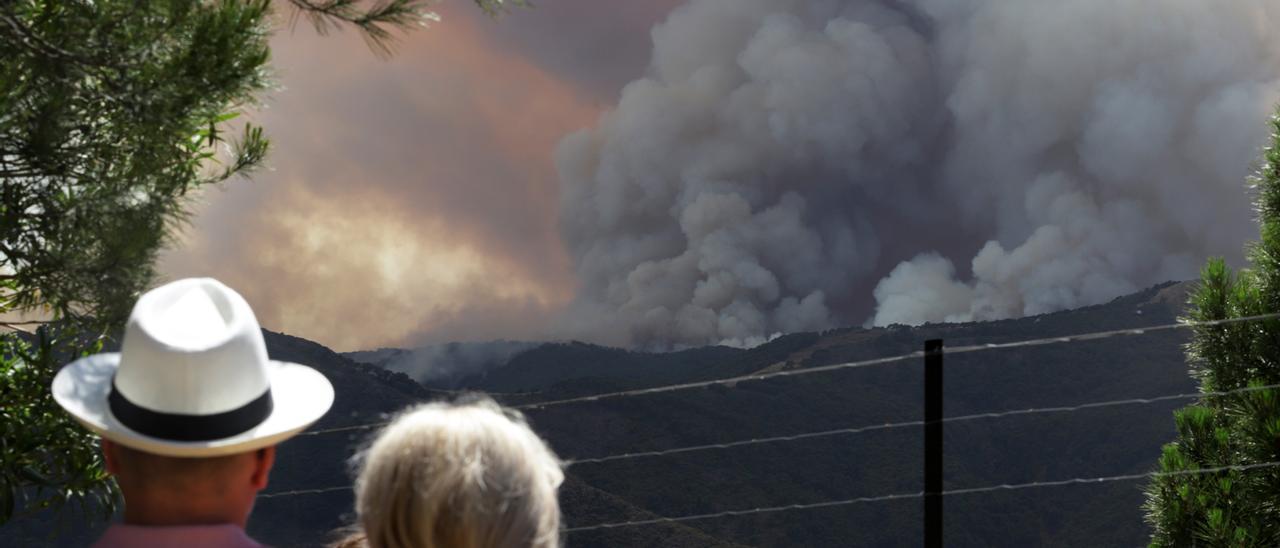 Dos vecinos observn la columna de humo provocada por el incendio.