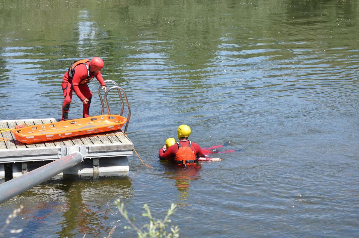 Dos bomberos rescatando a la víctima del río Órbigo, durante el simulacro.
