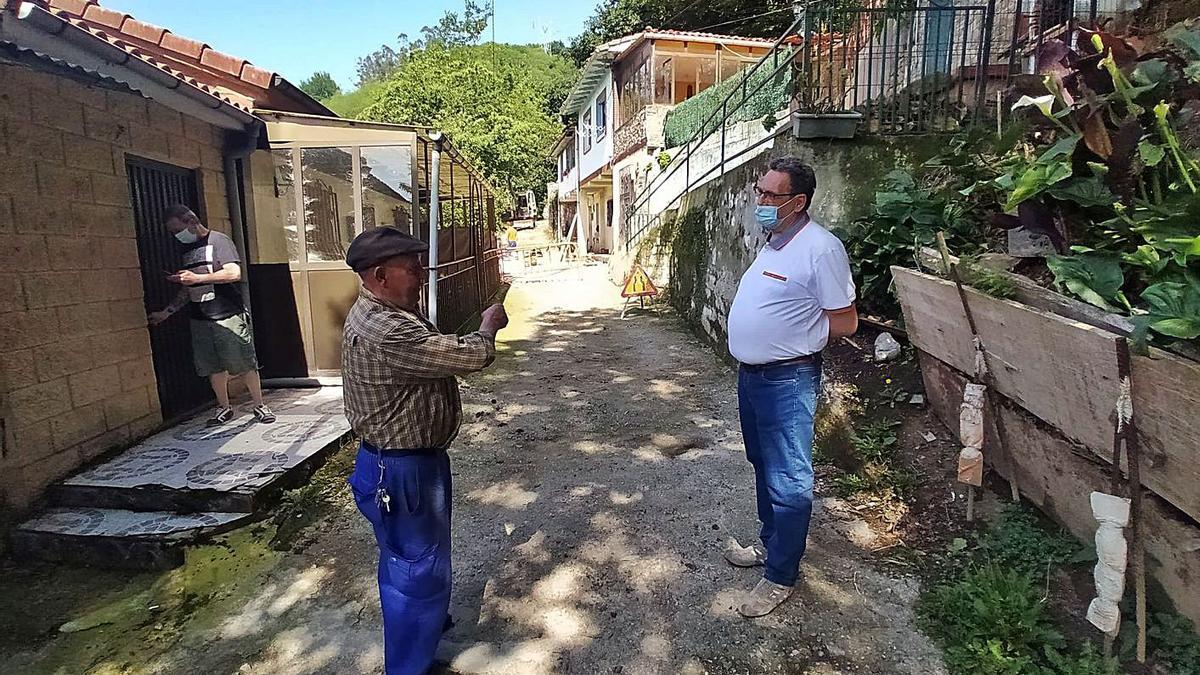 Ángel Luis Rubio, a la derecha, junto a los dos vecinos de Prau Redondu más afectados por las grietas, Miguel Suárez y Miguel Argüelles, este último cerrando la puerta de su casa. | D. M.