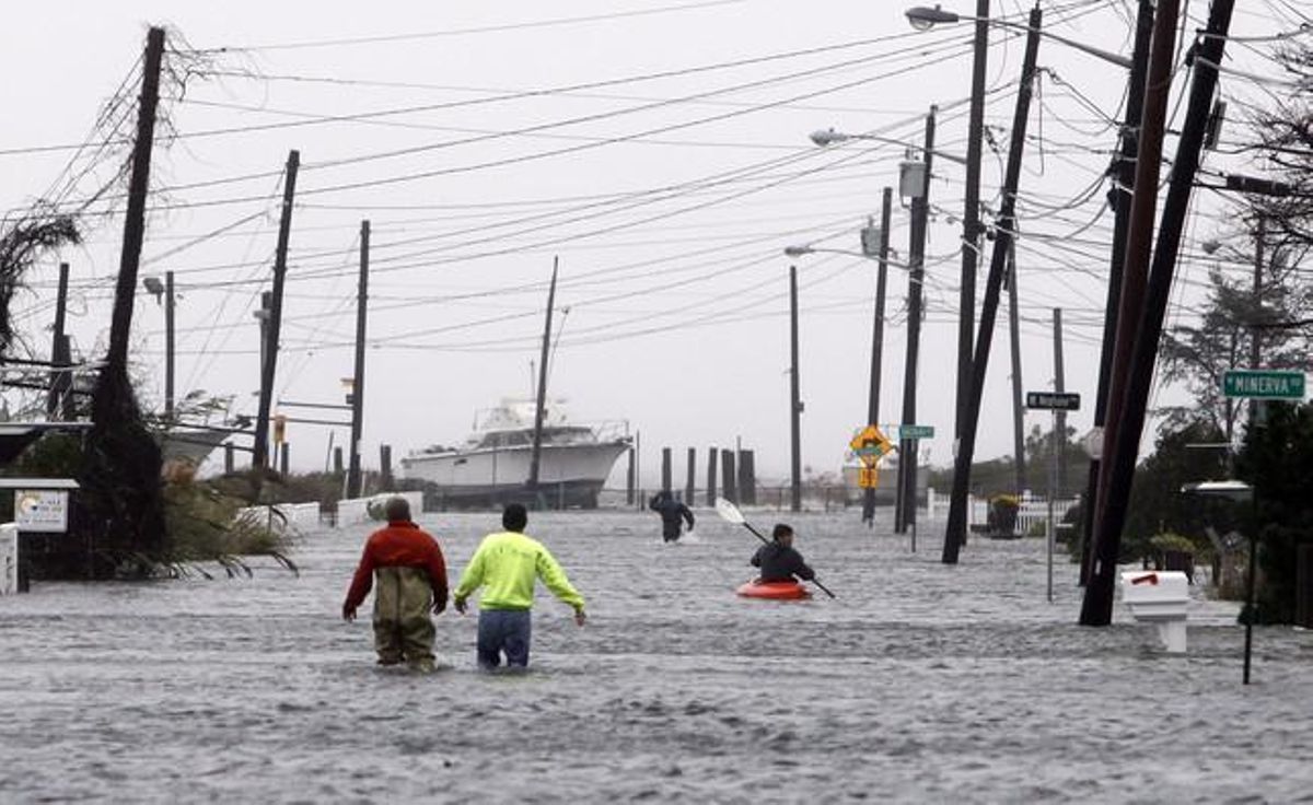 Els ciutadans de la zona de Lindenhurst, a Nova York, intenten avançar a peu o remant pels carrers inundats a causa les fortes pluges que ha deixat l’huracà al seu pas.