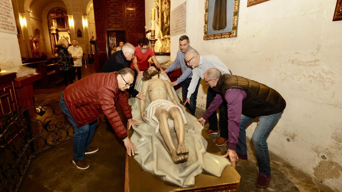 Varios hermanos trasladan la imagen del Sepulcro.