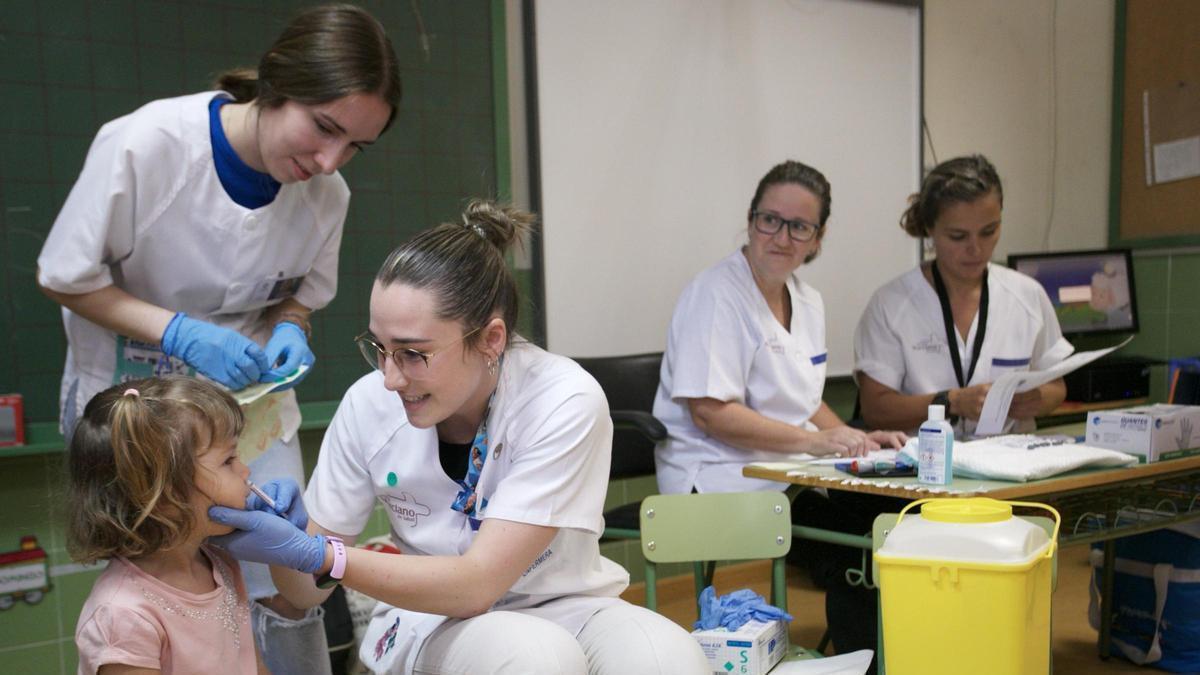 Enfermeras del Servicio Murciano de Salud administran la vacuna intranasal de la gripe a una niña en un colegio de Murcia.