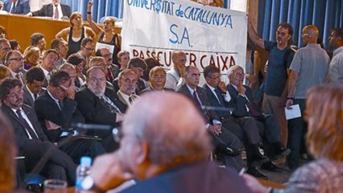 Un grupo de manifestantes despliega una pancarta ante el 'conseller' Mas-Colell (en primer plano, de espalda).