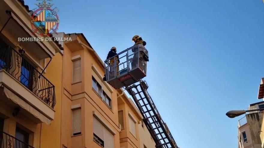 Bomberos retiran el canalón dañado con la ayuda de una autoescalera.