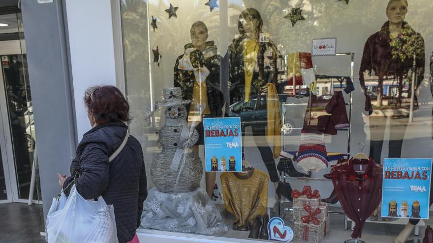 Una mujer pasa por delante del escaparate de un comercio.