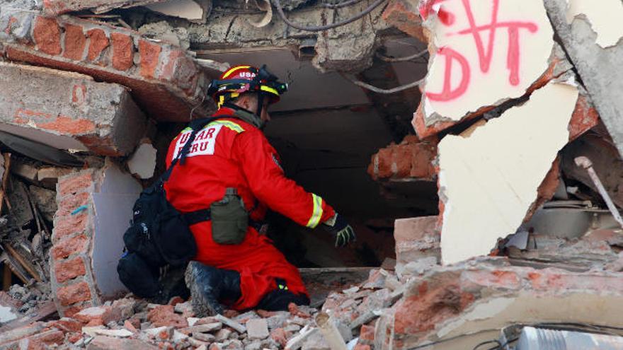 Un bombero peruano intenta localizar a posibles supervivientes bajo los escombros de un hotel.