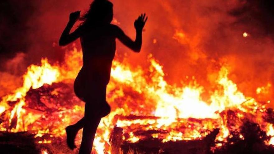 Una joven, al lado de la hoguera de San Juan encendida el año pasado en Porto Meloxo.
