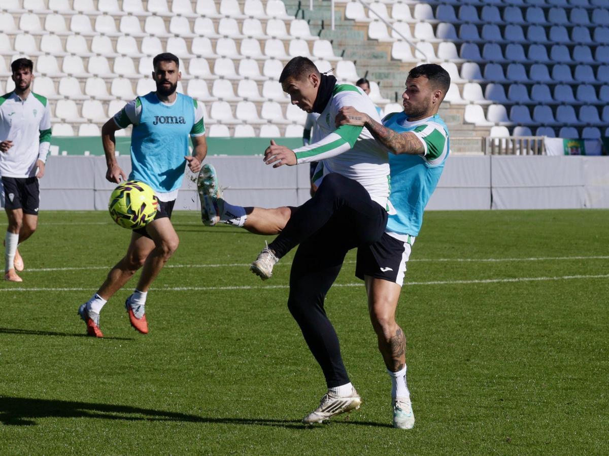 Álex Martín pugna por el esférico con Adrián Fuentes en un entrenamiento, con Sintes de fondo.