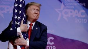 FILE PHOTO  U S  President Donald Trump hugs American flag at the Conservative Political Action Conference  CPAC  annual meeting at National Harbor near Washington  U S   March 2  2019  REUTERS Yuri Gripas File Photo