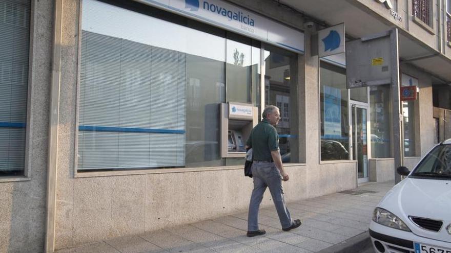 Un hombre camina por delante de una oficina de Novagalicia Banco. | bernabe / gutier