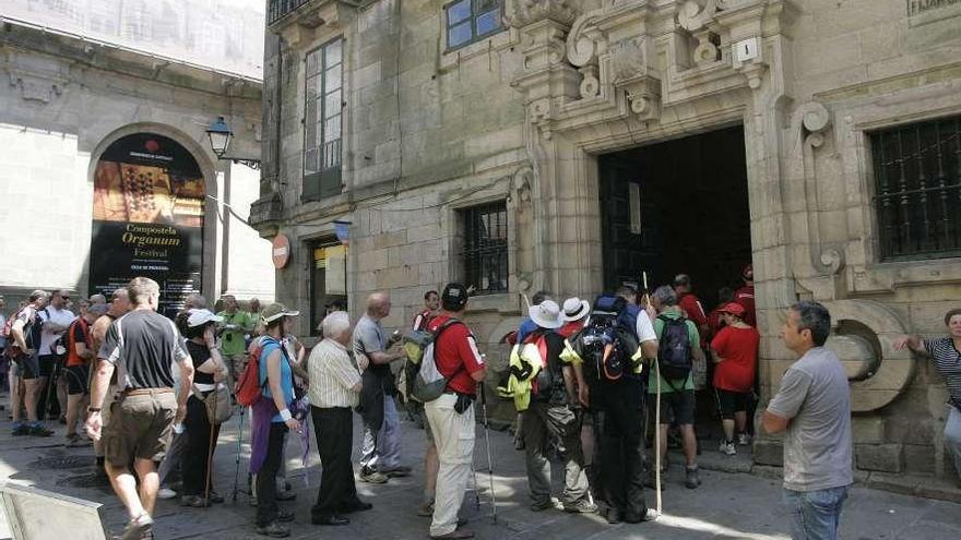 Un grupo de caminantes hacen cola en la Oficina del Peregrino de Santiago para sellar su Compostela. / x. a.