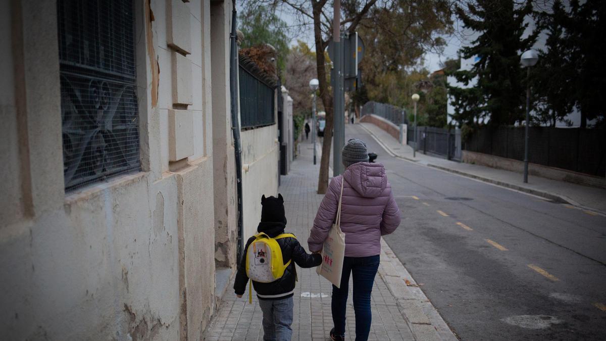 Una mujer lleva de la mano a un niño, en una foto de archivo