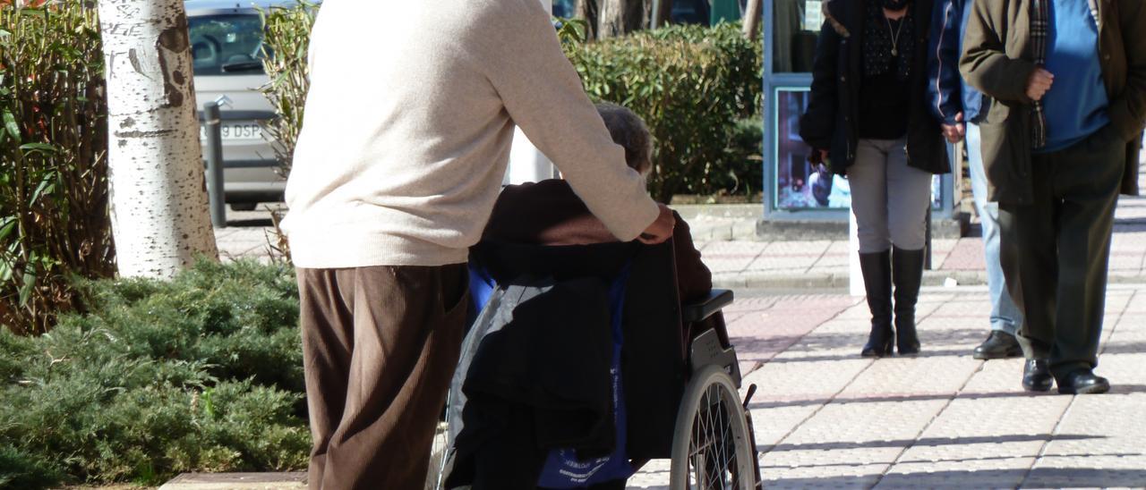 Un hombre pasea a una mujer dependiente en silla de ruedas