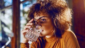 Una mujer bebe un vaso de agua.