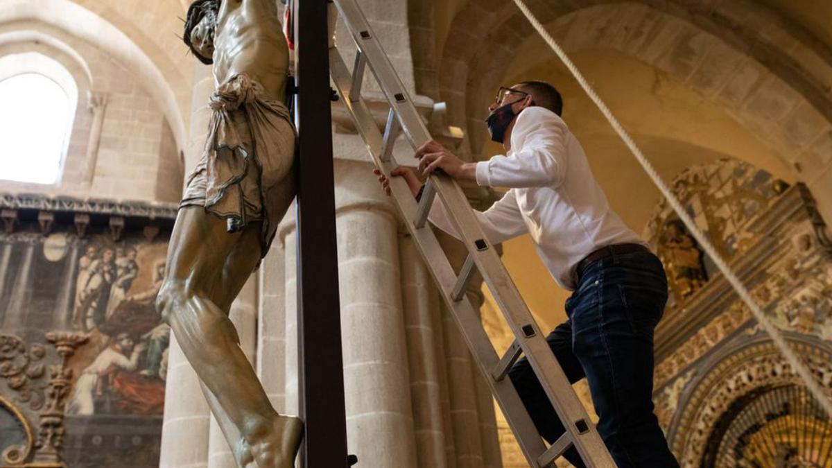 Un cofrade se dispone a retirar del Crucificado las cuerdas de sujeción.