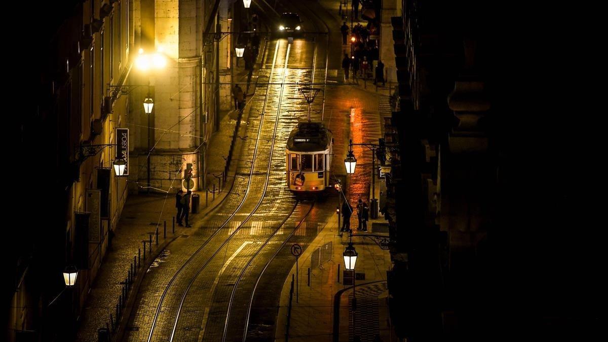 Un tranvía desciende por una sinuosa calle de Lisboa.