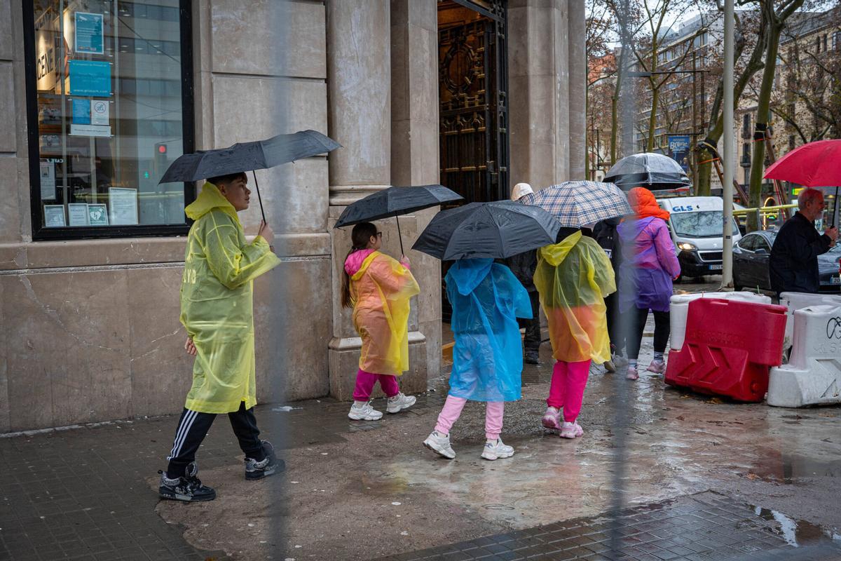 Gente con paraguas y chubasqueros por las lluvias en Barcelona.
