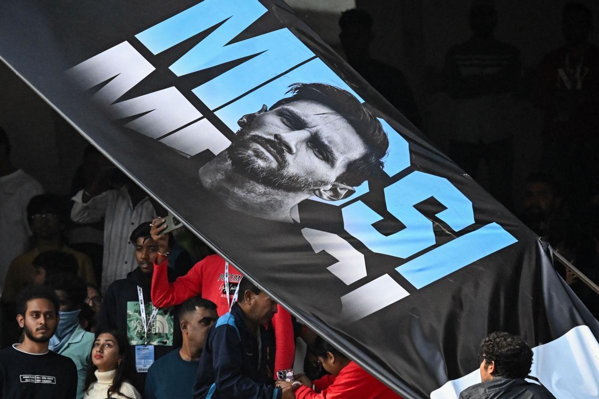 Spectators watch as a torn poster of Argentinas footballer Lionel Messi hangs from the roof during his GOAT Tour at Salt Lake Stadium in Kolkata on December 13, 2025. Angry spectators broke down barricades and stormed the pitch at a stadium in India after football star Lionel Messi, who is on a three-day tour of the country, abruptly left the arena. As a part of a so-called GOAT Tour, the 38-year-old Argentina and Inter Miami superstar touched down in the eastern state of West Bengal early on December 13, greeted by a chorus of exuberant fans chanting his name. (Photo by Dibyangshu SARKAR / AFP)