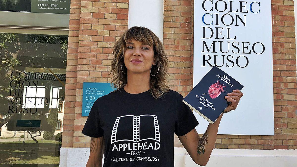 Asia Argento, posando con su libro y con una camiseta de la editorial malagueña, en la entrada del Museo Ruso de Málaga.