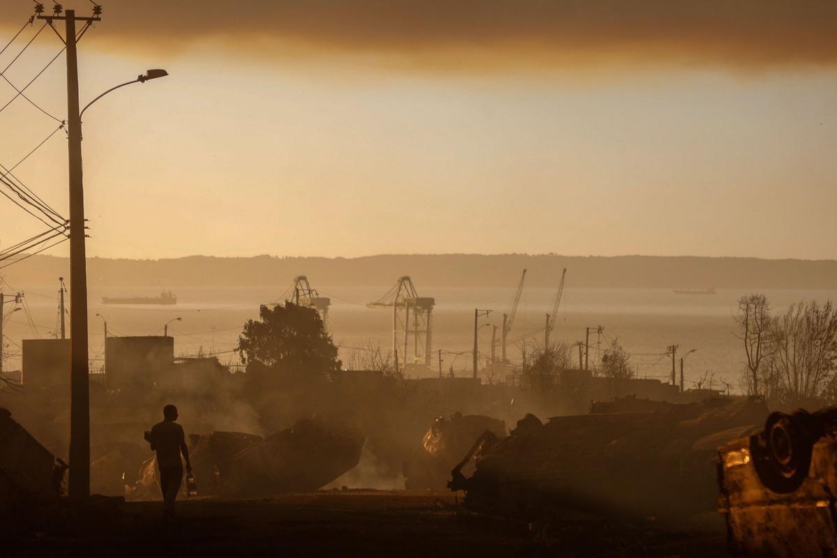 Un hombre transporta agua entre los automóviles quemados después de un incendio forestal en Concepción, Chile, el 18 de enero de 2026.