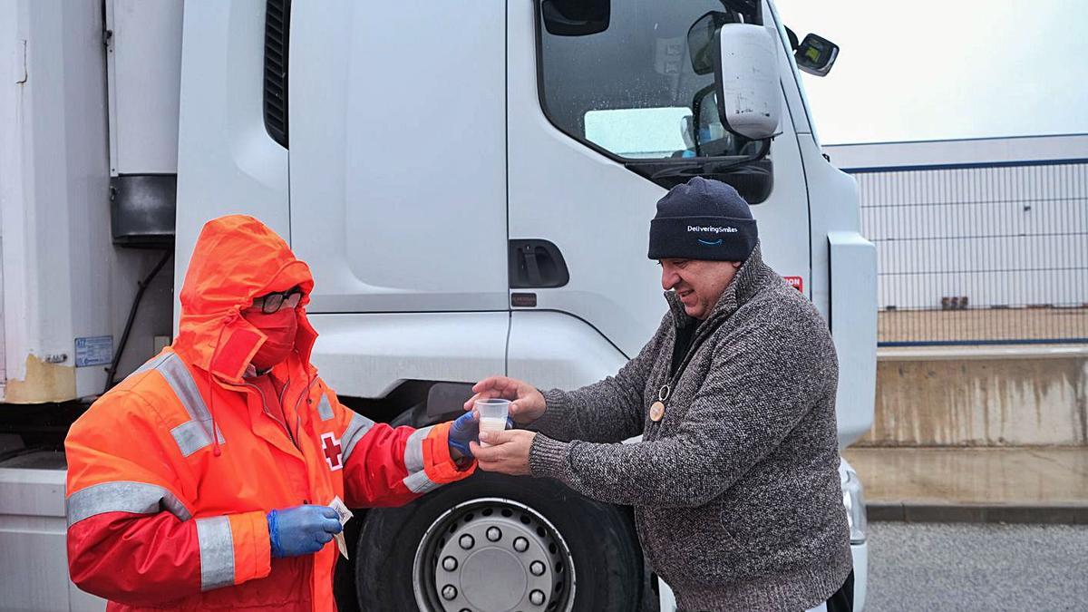 Un operario de Cruz Roja reparte bebida caliente a un camionero parado en Villena, ayer.  | ÁZEL ÁLVAREZ