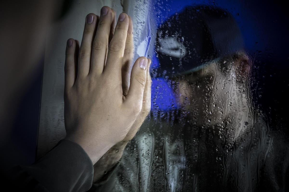 Un joven apoya la mano en un cristal - salud mental