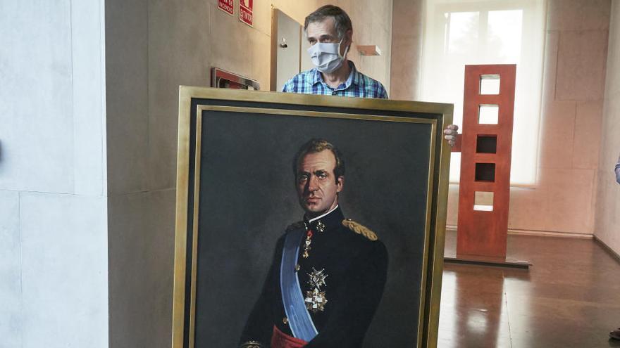 Un operario retira el retrato del rey emérito del Parlamento de Navarra