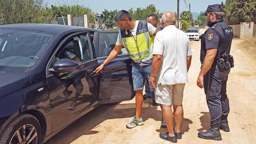 Los policías introducen en el coche a un detenido por narcotráfico en Sant Jordi.