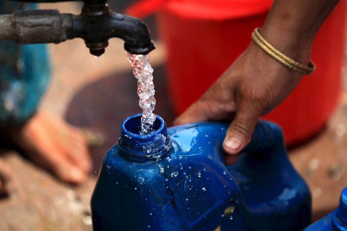 Una mujer india llena un bidón de agua potable en la India.