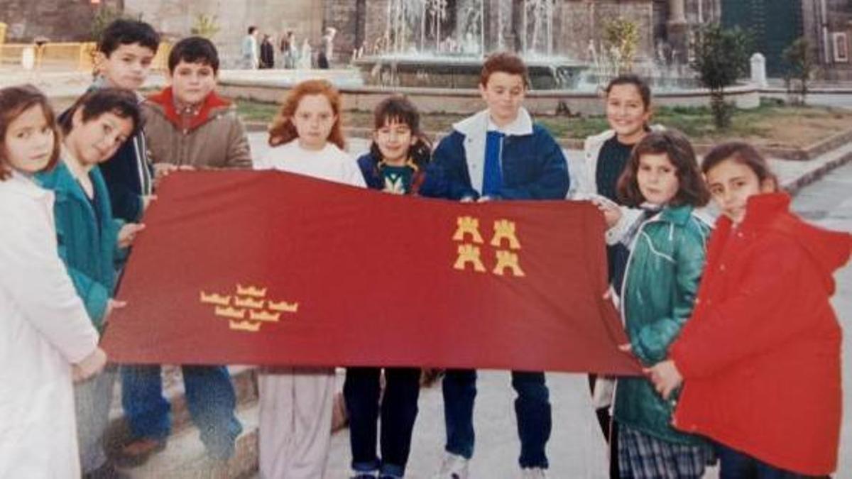 Niños en la Plaza Cardenal Belluga con una bandera de la Región. | CARM