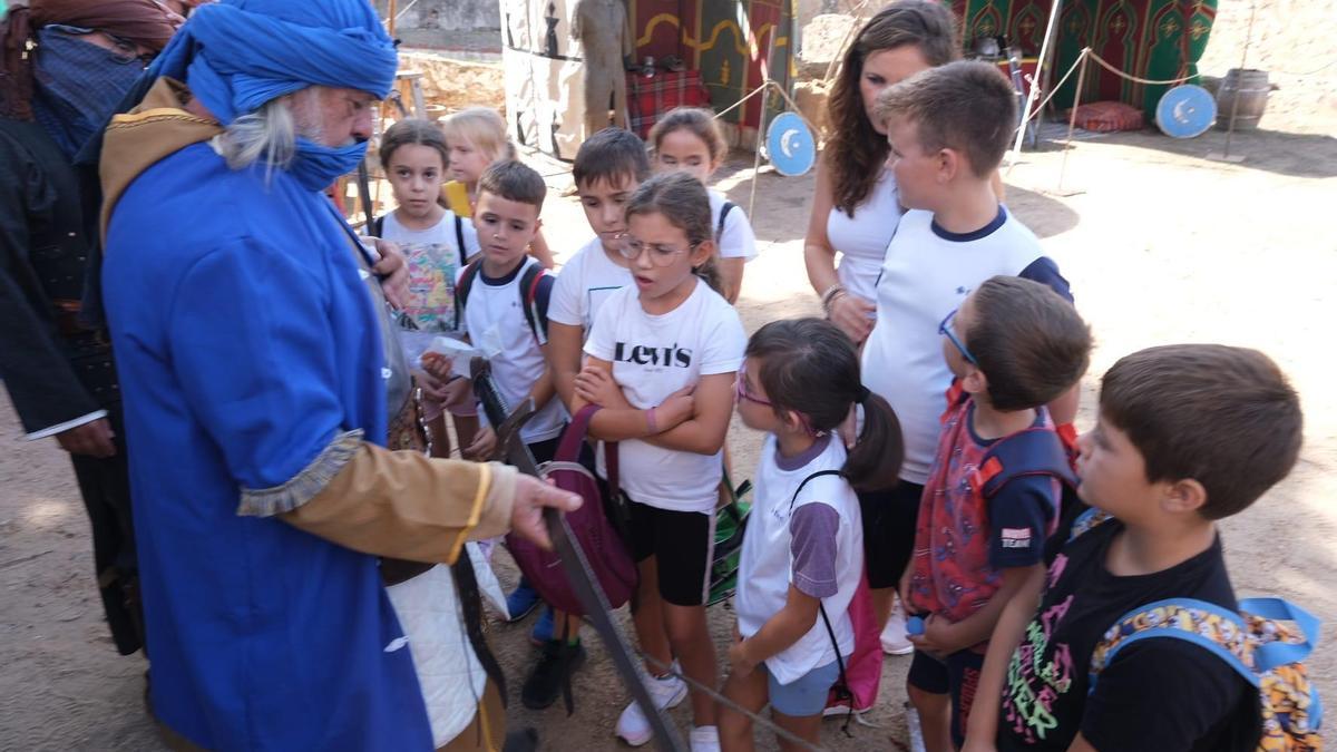 Un actor muestra armas a un grupo de niños, en el campamento de batalla.