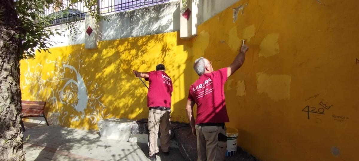 Dos alumnos del taller de empleo reparan una de las paredes