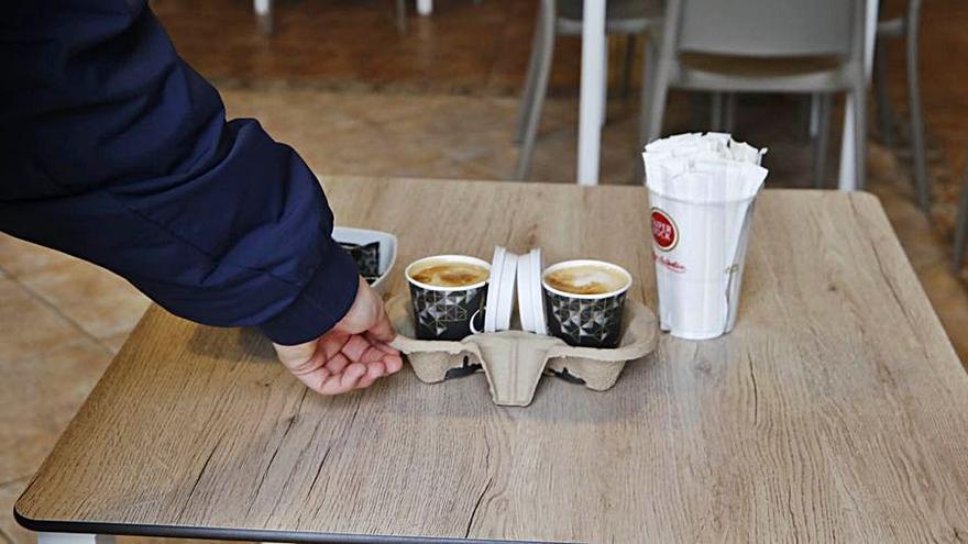 Un cliente coge dos cafés para llevar en un local de Montero Ríos.