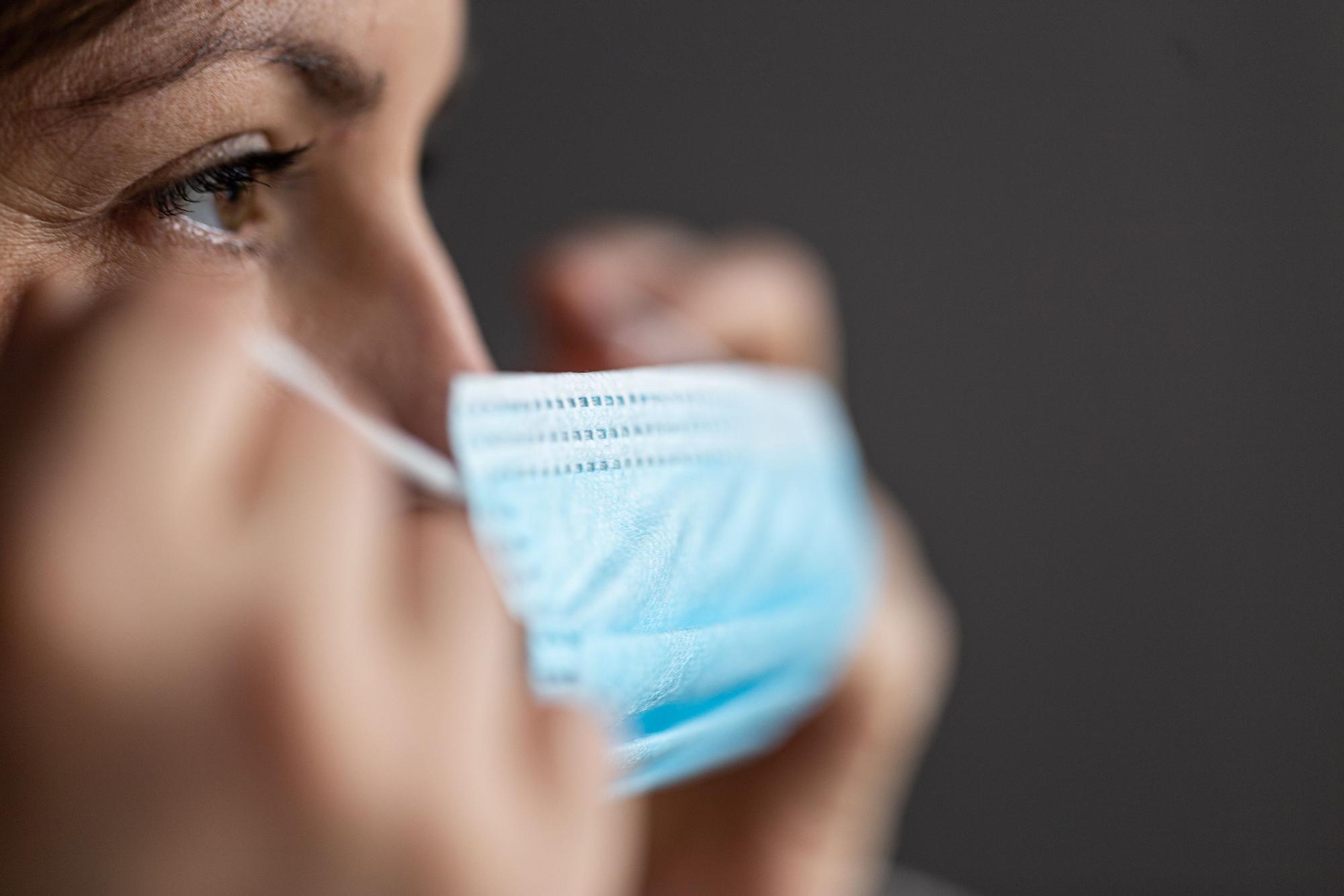 Una mujer se pone una mascarilla